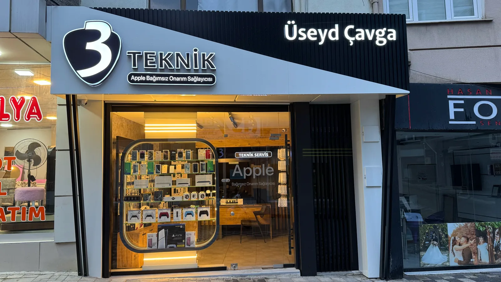 3 Teknik Servis'in dükkân cephesi akşam saatinde; aydınlatılmış '3 Teknik' tabelası ve vitrinde teşhir ürünleri.