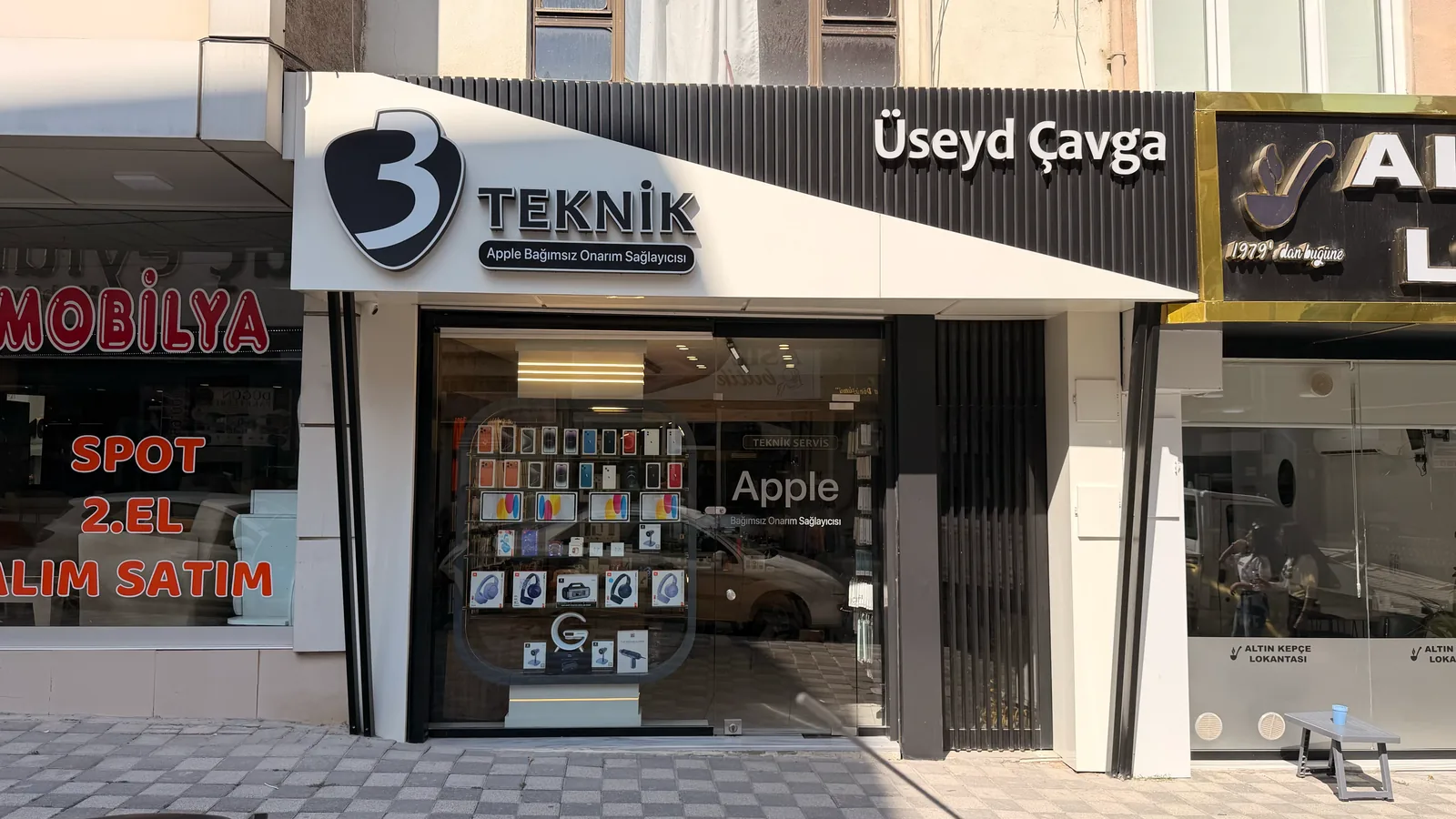 Gündüz çekilmiş dükkân cephesi; '3 Teknik' tabelası ve vitrindeki telefon ile aksesuar teşhiri okunaklı.